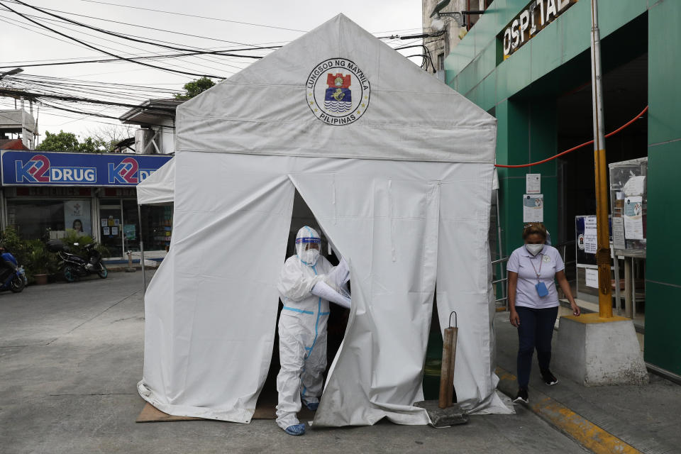 A health worker wearing a protective suit goes out of a tent with COVID-19 patients outside a hospital in Manila, Philippines on Monday, April 26, 2021. COVID-19 infections in the Philippines surged past 1 million Monday in the latest grim milestone as officials assessed whether to extend a monthlong lockdown in Manila and outlying provinces amid a deadly spike or relax it to fight recession, joblessness and hunger. (AP Photo/Aaron Favila)