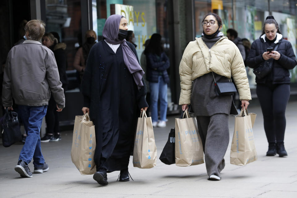 Women carrying shopping bags walk on Oxford Street in London, Monday, April 12, 2021. Millions of people in England will get their first chance in months for haircuts, casual shopping and restaurant meals on Monday, as the government takes the next step on its lockdown-lifting road map. (AP Photo/Kirsty Wigglesworth)
