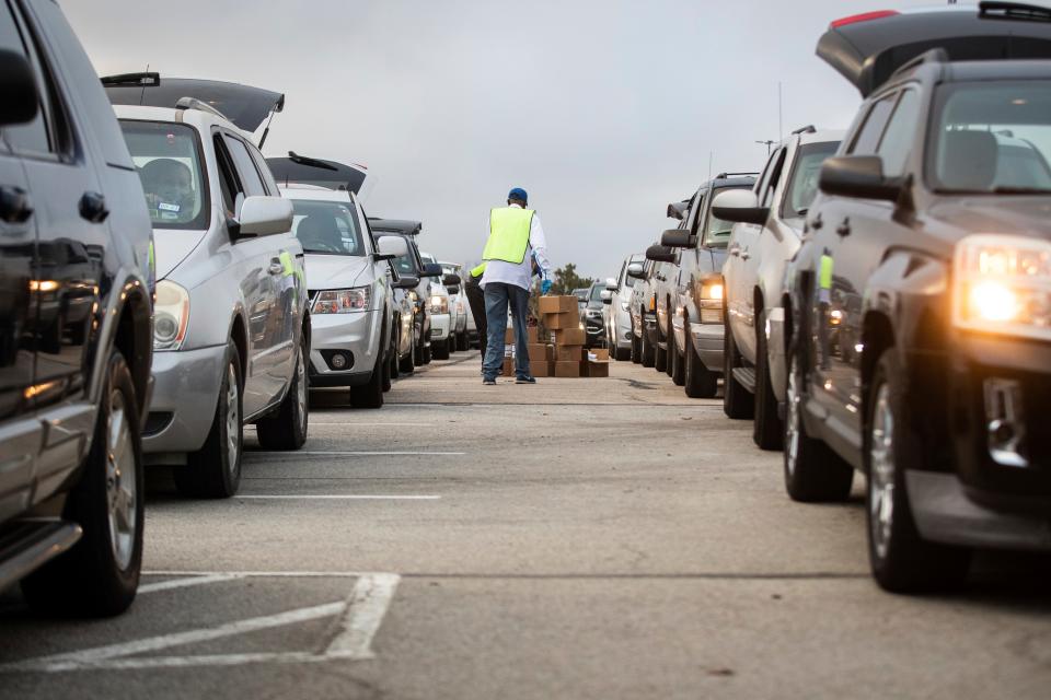 People line up in their cars to receive Thanksgiving meal boxes that include turkey and pantry items during the largest food giveaway of the Tarrant Area Food Bank amid the coronavirus pandemic Friday, Nov. 20, at AT&T Stadium parking lot in Arlington, Texas.