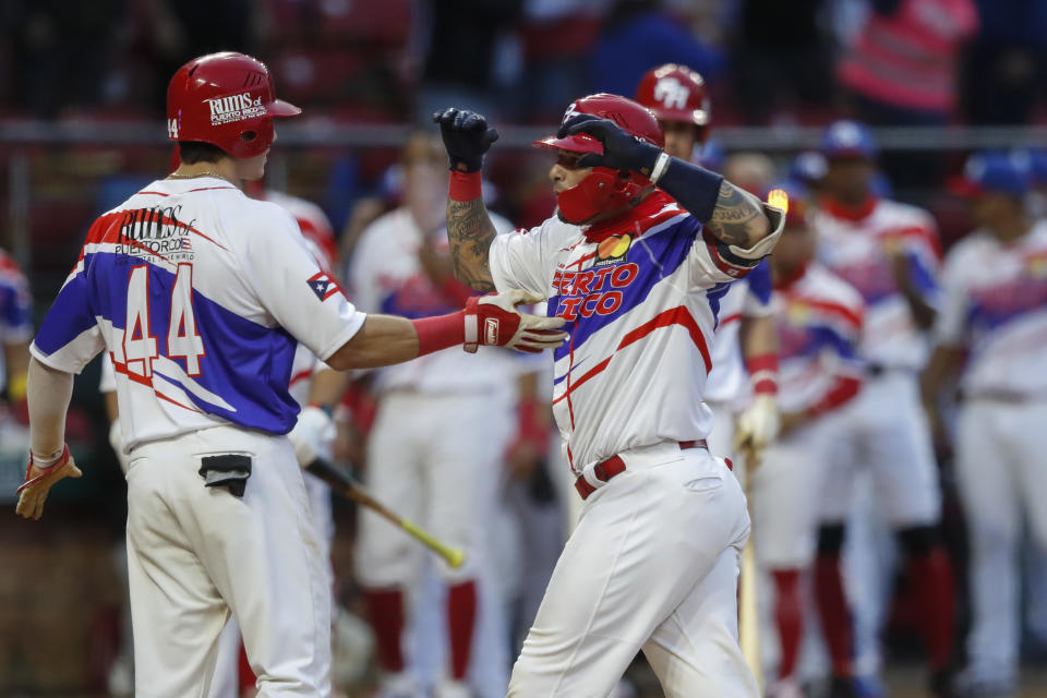 El puertorriqueño Yadier Molina es felicitado por su compañero Jarren Durán después de pegar un jonrón de dos carreras en la sexta entrada del juego ante Venezuela en la Serie del Caribe celebrada en Mazatlán, México, el lunes 1 de febrero de 2021. (AP Foto/Moises Castillo)