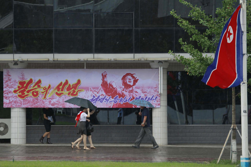 Residents walk along Changjon Street past a billboard poster reading "Conviction of sure victory" commemorating the 77th anniversary of Korea's Liberation in Pyongyang, North Korea, Monday, Aug. 15, 2022. (AP Photo/Cha Song Ho)