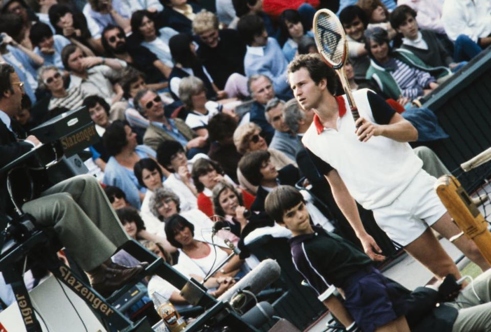 <div class="inline-image__caption"><p>John McEnroe by the net talking to the umpire in his chair, with a crowded grandstand in the background at Wimbledon in 1982.</p></div> <div class="inline-image__credit">Michael Cole/AELTC</div>