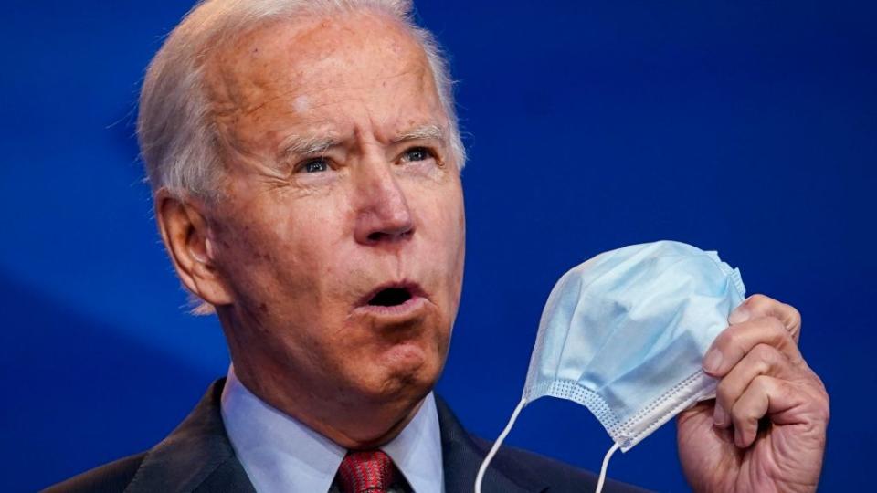 President-elect Joe Biden holds up a face mask while giving remarks about the Affordable Care Act and COVID-19 back in October after attending a virtual coronavirus briefing with medical experts at The Queen theater in Wilmington, Delaware. (Photo by Drew Angerer/Getty Images)