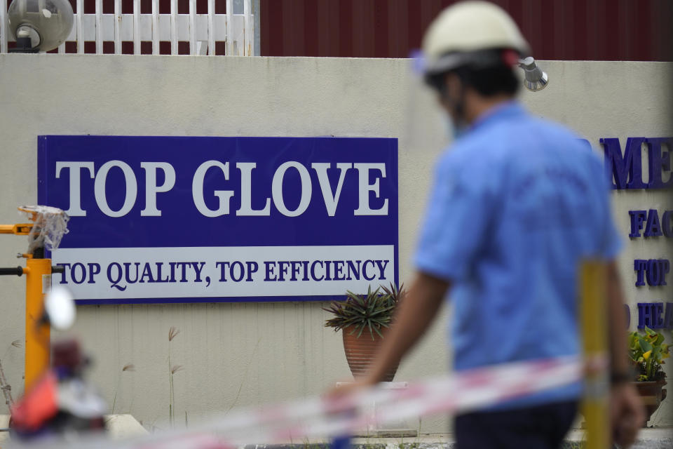 Workers from Top Glove walk outside Top Glove factory in Shah Alam, Malaysia, Wednesday, Nov. 25, 2020. Malaysia's Top Glove Corp., the world's largest maker of rubber gloves, says it expects delays in deliveries after more than 2,000 workers at its factories were infected by the coronavirus, raising the possibility of supply disruptions during the pandemic. (AP Photo/Vincent Thian)