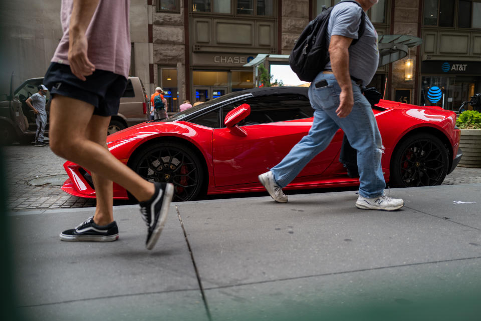 NEW YORK, NEW YORK - 18. JULI: D'Leit trëppelen vun engem Lamborghini Auto laanscht Wall Street am Finanzbezierk vu Manhattan den 18. Juli 2022 zu New York City. Globale Mäert bleiwen onbestänneg wéi d'Inflatioun an den USA e 40-Joer Héich erreecht huet, während d'Brennstoffpräisser ugefaang hunn ze falen. Trotz der Onsécherheet verbréngen d'Konsumenten weider wéi de Verkafsverkaaf tëscht Mee a Juni 1% eropgaang ass.