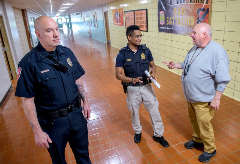 Demario Boone, middle, director of school safety for Peoria Public Schools, chats with custodian Scott Heathcoat, right, while resource officer Dylan Latta keeps an eye on the hallways at Manual High School in South Peoria.