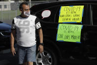 Disney employee Manuel Ortiz tapes signs on is car during a protest to demand a safe reopening amid the coronavirus pandemic Saturday, June 27, 2020, in Anaheim, Calif. Workers are demanding regular testing, stricter cleaning protocols and higher staffing levels. Disney had originally proposed reopening on July 17th but announced this week it was postponing. (AP Photo/Marcio Jose Sanchez)
