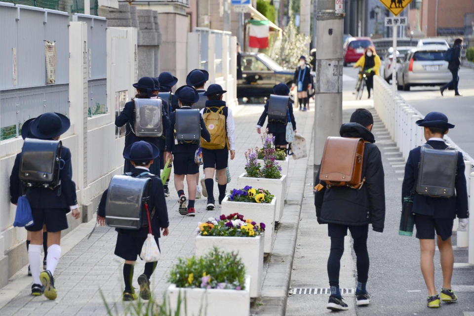 Elementary school students go to their school in Osaka, western Japan, Friday morning, Feb. 28, 2020, a day after Japanese Prime Minister Shinzo Abe's announcement. Abe asked all elementary, middle and high schools nationwide on Thursday to close until late March from March 2 to help control the spread of the new virus in the country. (Yoshihiko Imai/Kyodo News via AP)