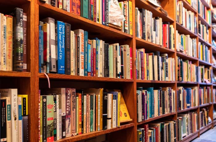 Bookshelves filled with a variety of books arranged upright. The shelves are densely packed, indicating a well-stocked library or bookstore