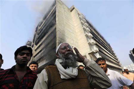 An employee cries in front of a Standard Group garment factory which was on fire in Gazipur November 29, 2013. There were no reports of casualties in the fire. REUTERS/Andrew Biraj