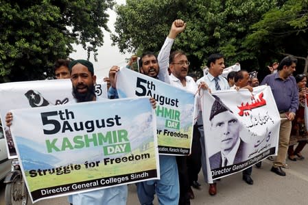 Demonstrators hold signs and chant slogans as they march in solidarity with the people of Kashmir, during a rally in Karachi