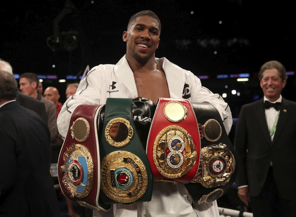 Anthony Joshua celebrates with his belts after victory over Joseph Parker to become the WBA, IBF and WBO heavyweight champion at the Principality Stadium in Cardiff, Wales, Saturday March 31, 2018. (AP)