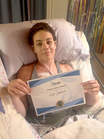 <p>Cat Janice/Instagram</p> Cat Janice poses with a music award from her hospital bed.