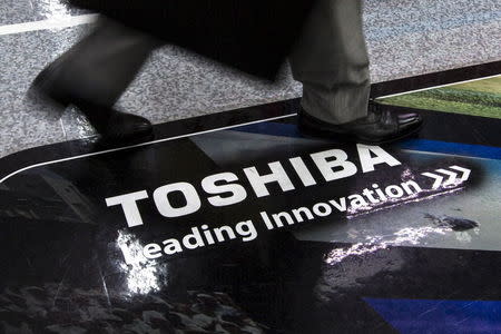 A man walks past a logo of Toshiba Corp at an electronics store in Tokyo July 21, 2015. REUTERS/Thomas Peter