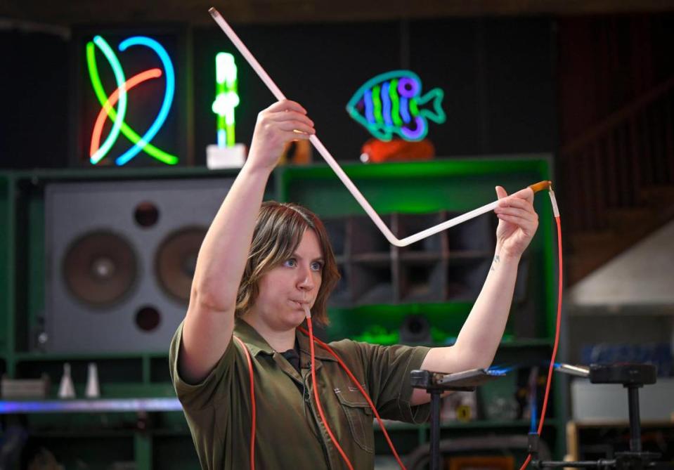 Olivia Shelton, a neon tube bender and project manager, blows into and shapes a glass tube at Element Ten, a neon studio on Troost Avenue.