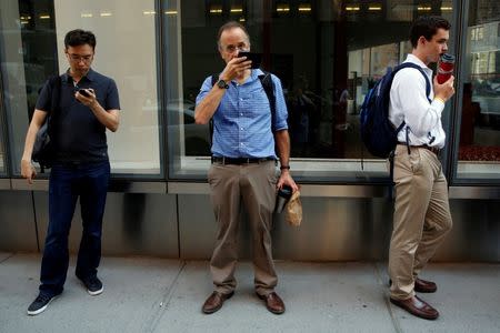 Commuters wait nearby as police investigate the scene near an SUV in which a man suspected of causing a bomb scare barricaded himself, causing an hours-long standoff and the shutdown of a mid-Manhattan area in New York City, New York, U.S. July 21, 2016. REUTERS/Brendan McDermid