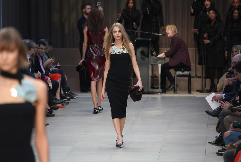 British model Cara Delevingne, Model Of The Year at the 2012 British Fashion Awards, wears a design created by Burberry Prorsum, as musician Tom Odell performs on the piano, during London Fashion Week, at Kensington Gardens in west London, Monday, Feb. 18, 2013. (Photo by Joel Ryan/Invision/AP)