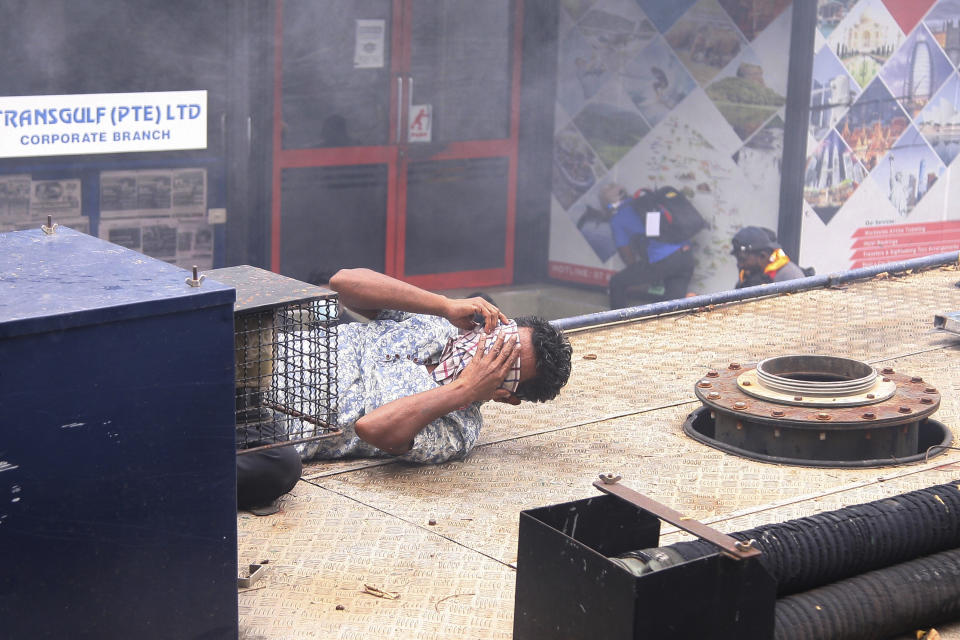 A man covers his face after a tear gas shell fired by police to disperse the protesters landed near him in Colombo, Sri Lanka, Saturday, July 9, 2022. Sri Lankan protesters demanding that President Gotabaya Rajapaksa resign forced their way into his official residence on Saturday, a local television report said, as thousands of people took to the streets in the capital decrying the island nation's worst economic crisis in recent memory. (AP Photo/Amitha Thennakoon)