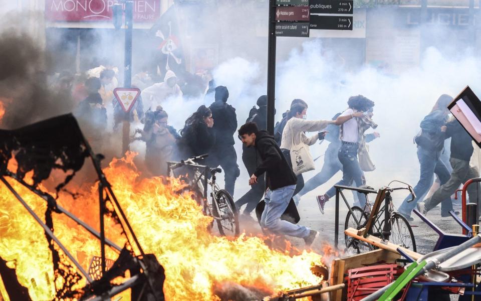 Protesters run in tear gas smoke and street fire in Toulouse - CHARLY TRIBALLEAU/AFP via Getty Images)