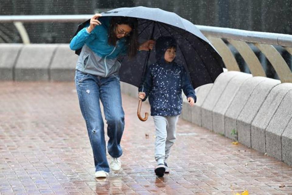A woman and a child struggle with strong winds as Hong Kong hoisted typhoon signal no 8 around noon on 8 October (AFP via Getty Images)