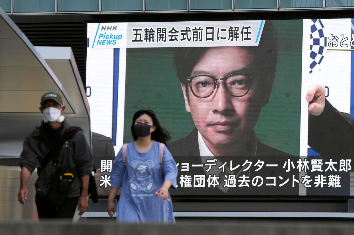 Pedestrians walk past a huge display showing the sacking of Kentaro Kobayashi (EPA)