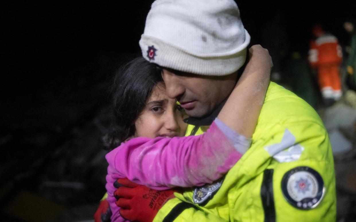 Police officer Zekeriya Yildiz hugs his daughter after they saved her from the rubble in Hatay - AFP