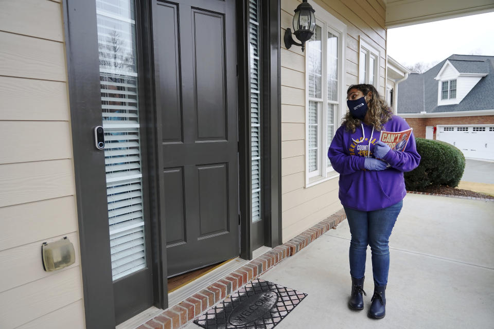 Stephanie Lopez-Burgus talks to a voter while canvassing the area for the Working Families Party about the U.S. Senate races, Wednesday, Dec. 16, 2020, in Lawrenceville, Ga. (AP Photo/Tami Chappell)
