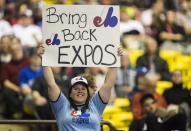 FILE - In this April 3, 2015, file photo, a fan holds up a sign during a pregame ceremony as the Toronto Blue Jays face the Cincinnati Reds in an exhibition baseball game in Montreal. The Tampa Bay Rays have received permission from Major League Baseball's executive council to explore a plan that could see the team split its home games between the Tampa Bay area and Montreal. (Paul Chiasson/The Canadian Press via AP, File)