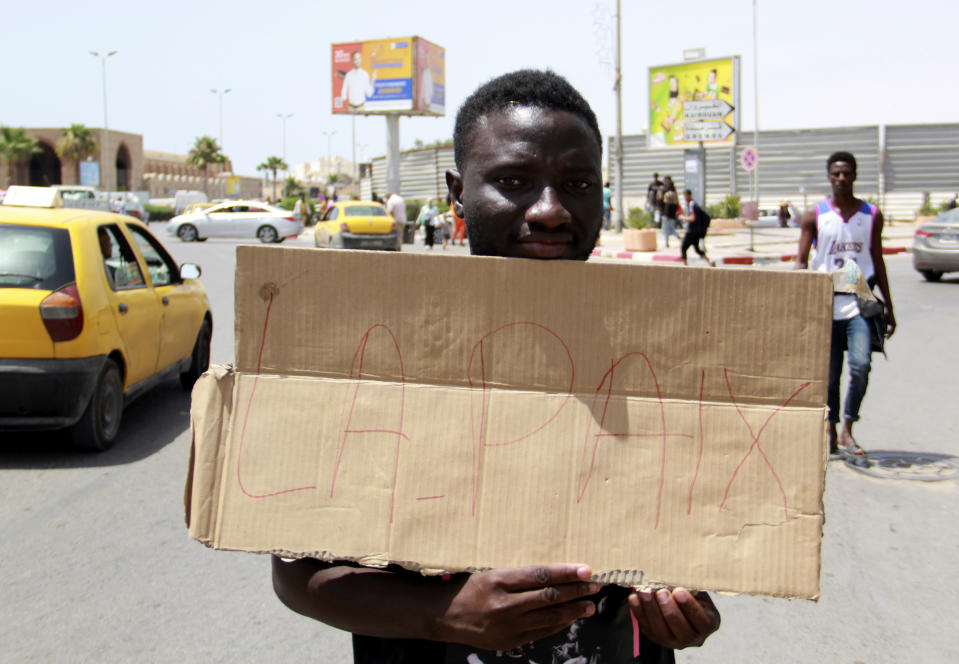 A migrant holds a placard reading "Peace"" during a gathering in Sfax, Tunisia's eastern coast, Friday, July 7, 2023. Tensions spiked dangerously in a Tunisian port city this week after three migrants were detained in the death of a local man, and there were reports of retaliation against Black foreigners and accounts of mass expulsions and alleged assaults by security forces. (AP Photo)