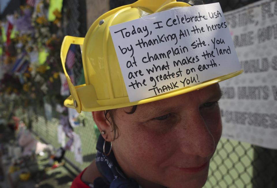 Hialeah resident Alison Kairuz is shown after pinning her hand-made sign to the fence in support of families and friends who lost love ones at the memorial site for victims of the partially collapsed South Florida condo building Champlain Towers South in Surfside, Fla., Sunday, July 4, 2021. (Carl Juste/Miami Herald via AP)