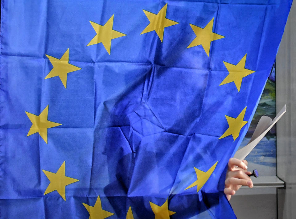 A woman exits a voting cabin with curtains depicting the European Union in Baleni, Romania, Sunday, May 26, 2019. The ruling Social Democratic Party (PSD) suffered a major blow in the European Parliament elections according to the country's only exit poll. (AP Photo/Andreea Alexandru)