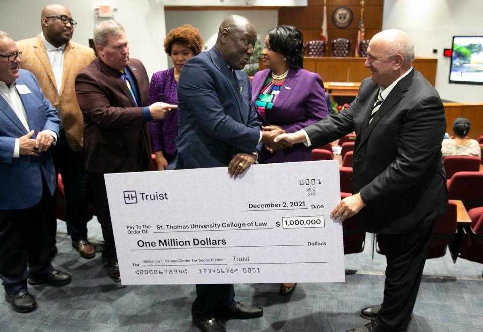 Attorney Ben Crump shakes hands with Herman Russomano, chair emeritus of St. Thomas University’s School of Law Board of Advisors, while holding a $1 million check representing a leadership grant from Truist Financial Corporation’s charitable arm on Dec. 2, 2021. Truist made the initial funding for the newly announced Benjamin L. Crump Center for Social Justice at St. Thomas University.