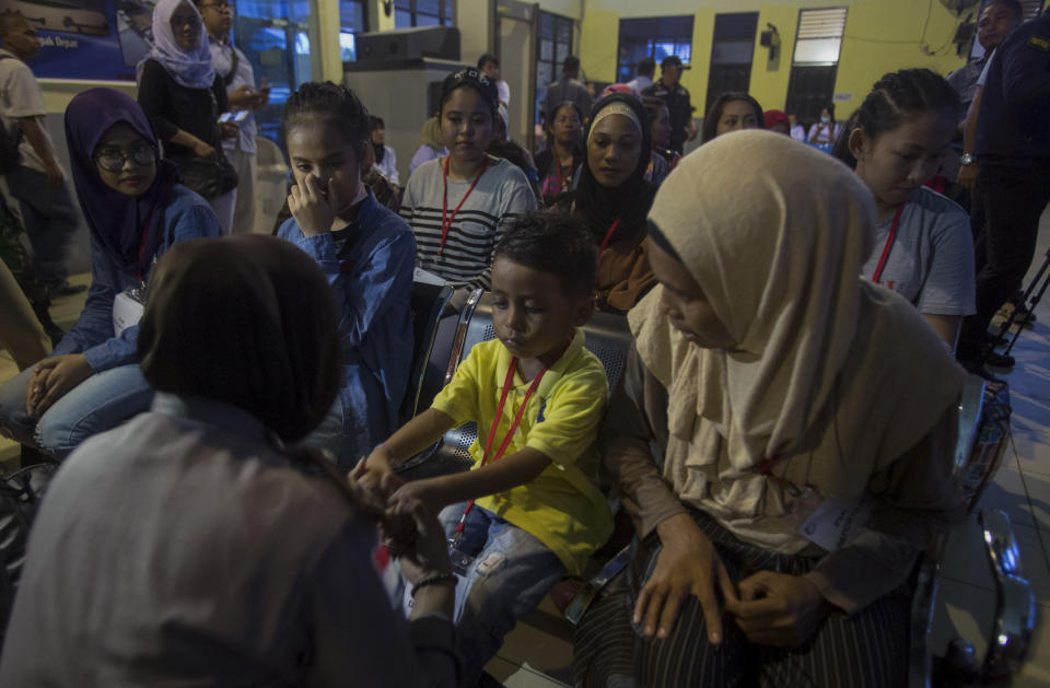 A police officer plays with a child deported with his Indonesian family for working illegally in Malaysia, at an immigration office processing center in Nunukan, Indonesia, on Thursday, Dec. 6, 2018. (AP Photo/Binsar Bakkara)