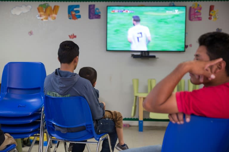 A father and son seeking asylum watch a World Cup match at a Catholic Charities relief center in McAllen, Texas, near the border with Mexico