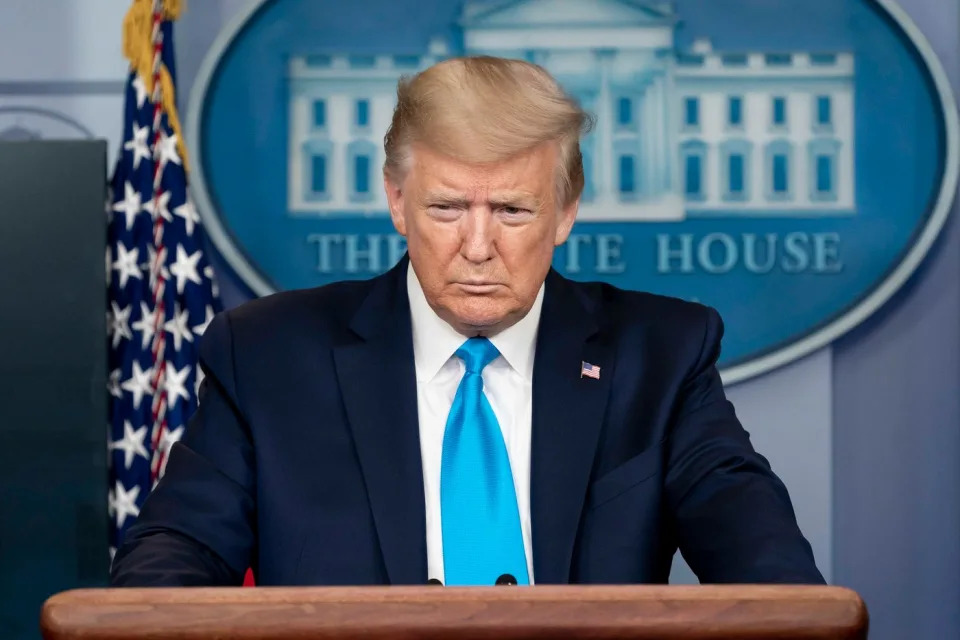 Former President Donald Trump speaking with reporters from behind the presidential podium.