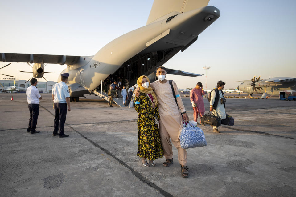 People evacuated from Afghanistan pose in front of a German Bundeswehr airplane after arriving at the airport in Tashkent, Uzbekistan, Tuesday, Aug. 17, 2021. The federal armed forces evacuates German citizens and local Afghan forces from Kabul. (AP Photo/Bundeswehr via AP)