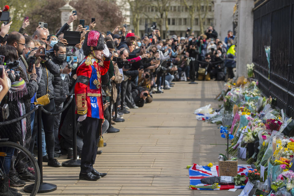 A man arrives to lay a floral tribute outside Buckingham Palace, London, following the announcement of the death of the Britain's Prince Philip at the age of 99. Prince Philip, the irascible and tough-minded husband of Queen Elizabeth II who spent more than seven decades supporting his wife in a role that both defined and constricted his life, has died, Buckingham Palace said Friday. He was 99. (Ian West/PA via AP)