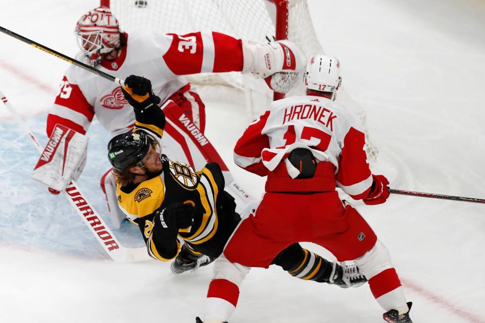 Boston Bruins' David Pastrnak (88) falls while working against Detroit Red Wings' Filip Hronek (17) in front of goalie Alex Nedeljkovic (39) during the first period of an NHL hockey game Tuesday, Nov. 30, 2021, in Boston.