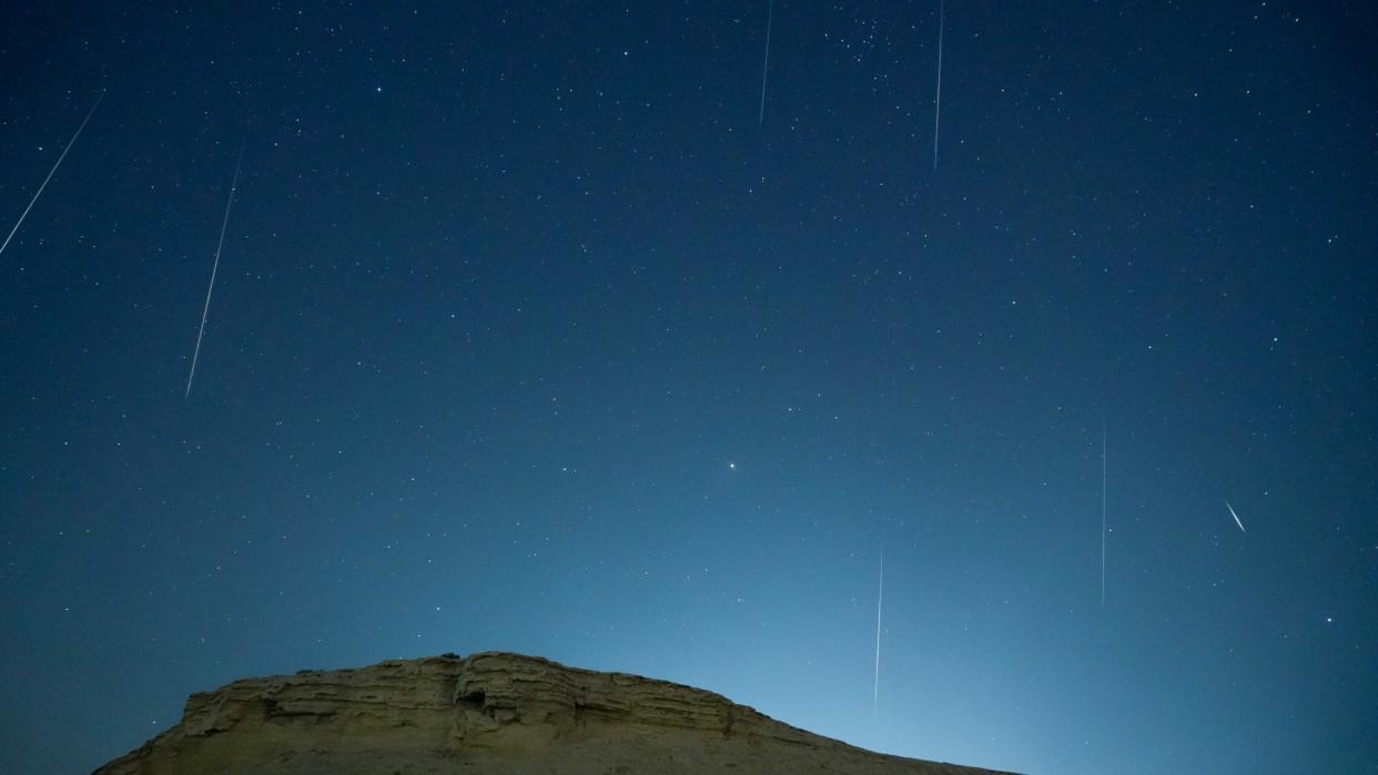  Meteors streak through a dark night sky. 