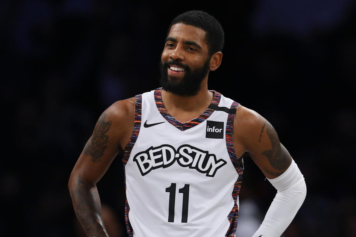 Kyrie Irving with a slight smile and his hands on his hips during a game.