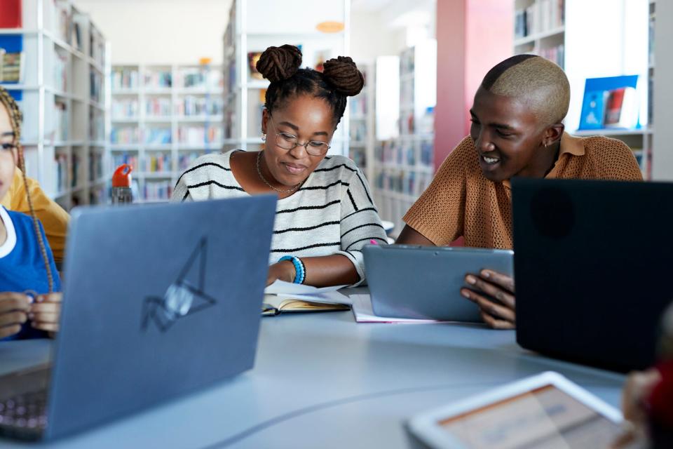 Smiling student with female friend at desk