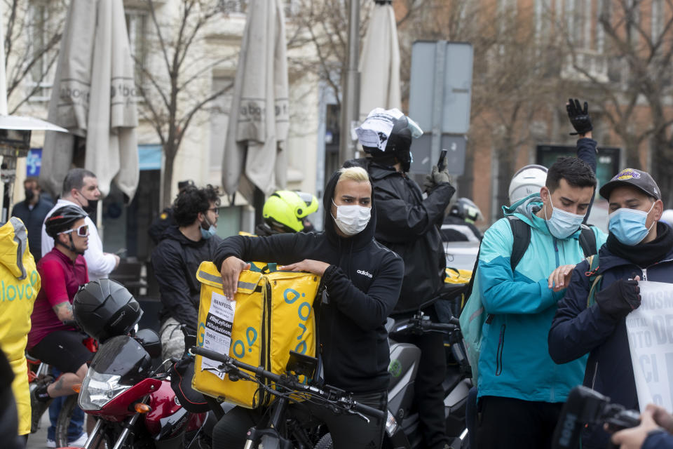 Delivery riders gather to protest outside the Spanish parliament in Madrid, Wednesday March 3, 2021. Food delivery workers have staged protests across Spain, urging the government to approve a promised law granting them the right to choose between being company staff or self-employed. Media reports said more than 2,000 delivery riders gathered to protest in at least 10 Spanish cities on Wednesday. (AP Photo/Paul White)