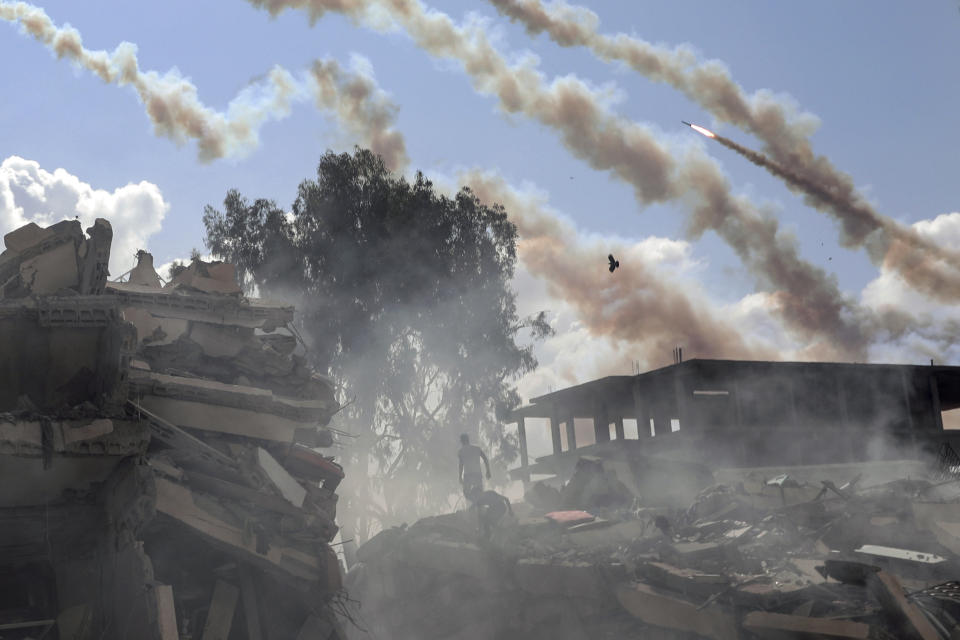 En la imagen, cohetes lanzados desde la Franja hacia Israel pasan sobre edificios destruidos por los ataques israelíes sobre el enclave, en el centro de Gaza, el 19 de octubre de 2023. (AP Foto/Mohammed Dahman)