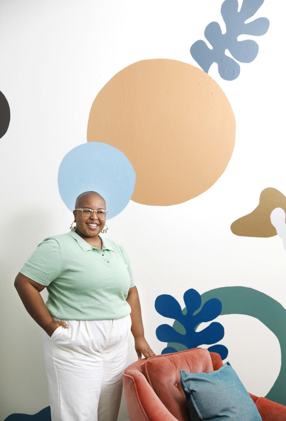 The club's founder stands in front of a boldly patterned wall.