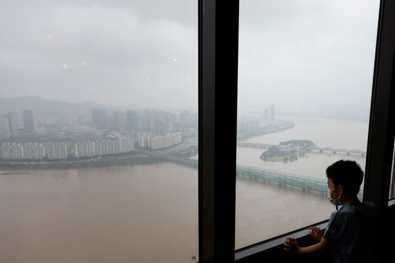 Boy looks down at a flooded Han River park from an observatory platform in Seoul