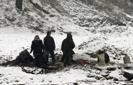 North Koreans wash collected coal cinder in a river at the North Korean town of Sinuiju, opposite the Chinese border city of Dandong, February 12, 2013. REUTERS/Stringer