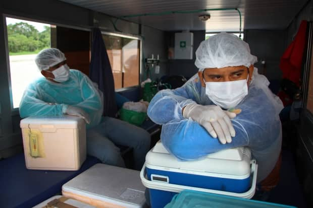 Health-care workers Diego Feitosa Ferreira, right, and Clemilton Lopes de Oliveira travel on a boat in the state of Amazonas in Brazil, on Feb. 12, to vaccinate residents with the Oxford-AstraZeneca COVID-19 vaccine. The product can be stored at refrigeration temperatures, which facilitates its use in remote areas.