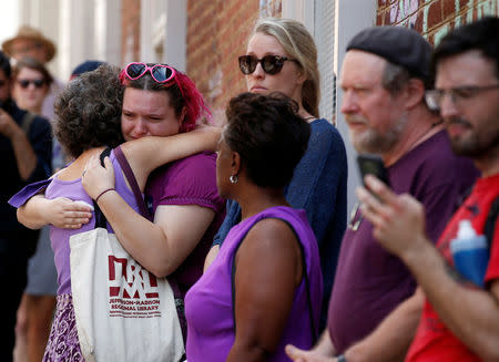 Women comfort each other at the site where Heather Heyer was killed when a suspected white nationalist crashed his car into anti-racist demonstrators in Charlottesville, Virginia, U.S., August 16, 2017. REUTERS/Joshua Roberts