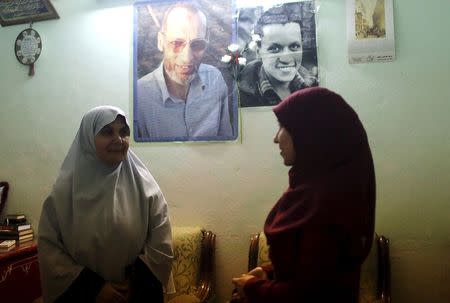 The wife, Asrar (L), and daughter, Asmaa, of Mahmoud Abdel Hadi pose for a picture beneath photographs of Hadi (top L) and his son Assem at the family home in the Nile Delta city of Mansoura, Egypt, July 28, 2015. REUTERS/Asmaa Waguih