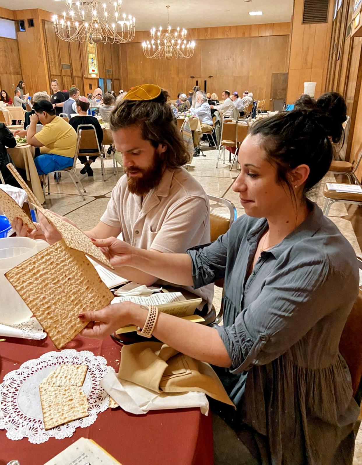 Debra Bishop, with her husband David Bishop nearby, prepares to break a piece of matzah during a Passover Seder on Wednesday at Emanuel Synagogue in Oklahoma City.